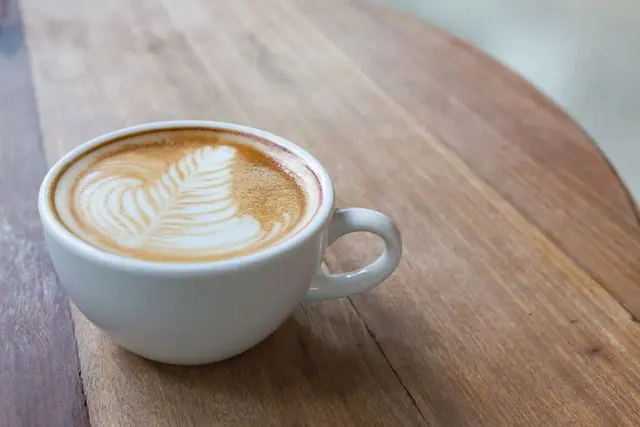 A cup of coffee on top of a wooden table.